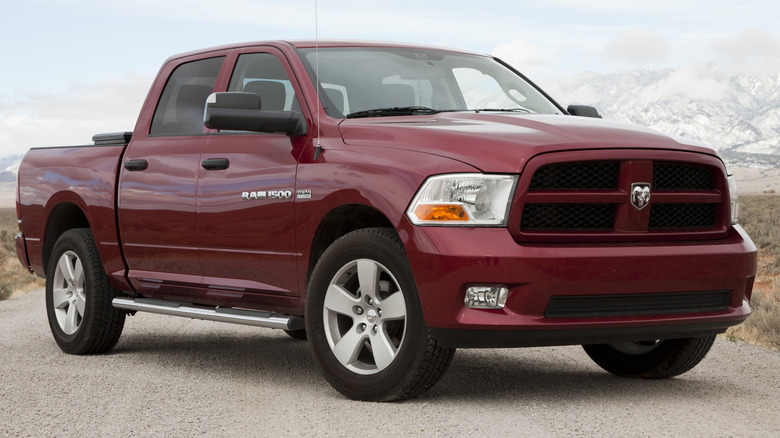 A dark red, modern Ram pickup truck parked diagonally on a rural road.