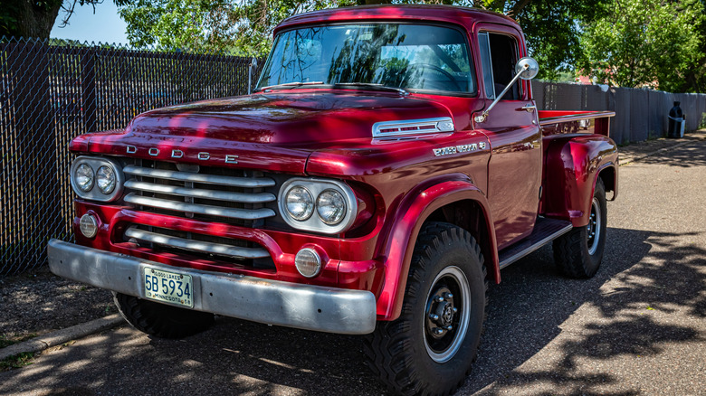 A 1958 red Dodge C Series pickup truck parked at a car show.