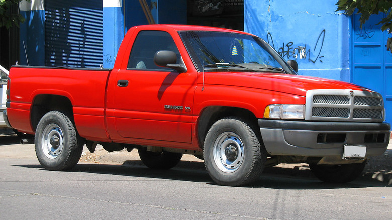 A red 1994 Dodge Ram pickup truck, with the classic big rig design, parked on a street.