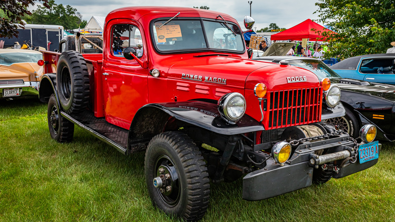 A bright red 1957 Dodge Power Wagon at a vintage car show.