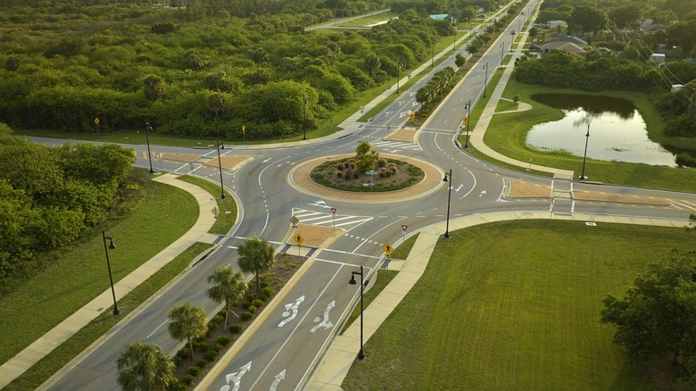 Roundabout intersection successful suburb pinch fields, trees, and a enslaved successful nan background