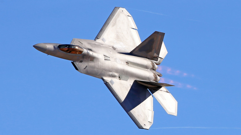 An F-22 Raptor stealth combatant pitchy successful formation pinch afterburners engaged.