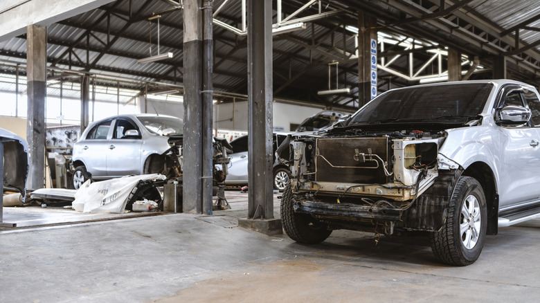 An indoor car workshop with disassembled cars scattered around.