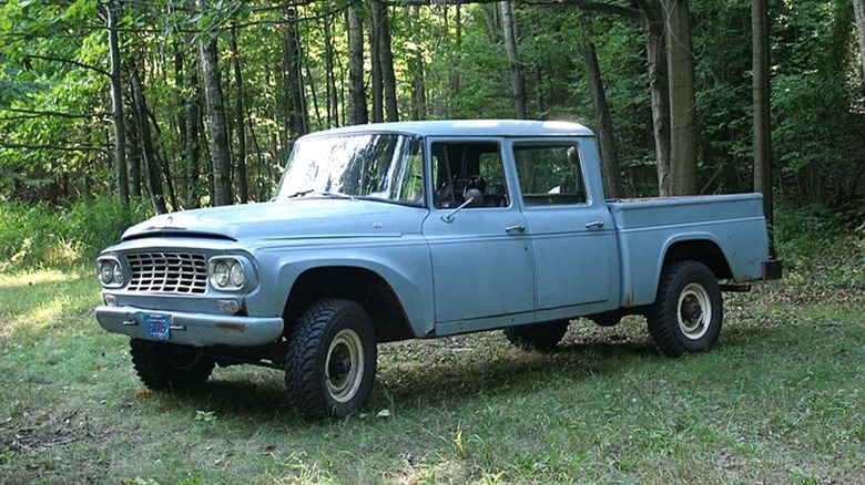 The front left 3/4 of a blue 1961 International Harvester Travelette quad cab parked in a forest