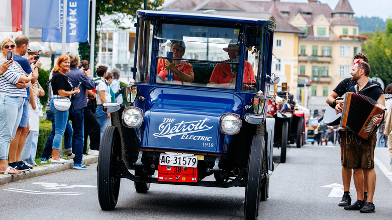 A vintage Detroit Electric car driving through a parade in Austria