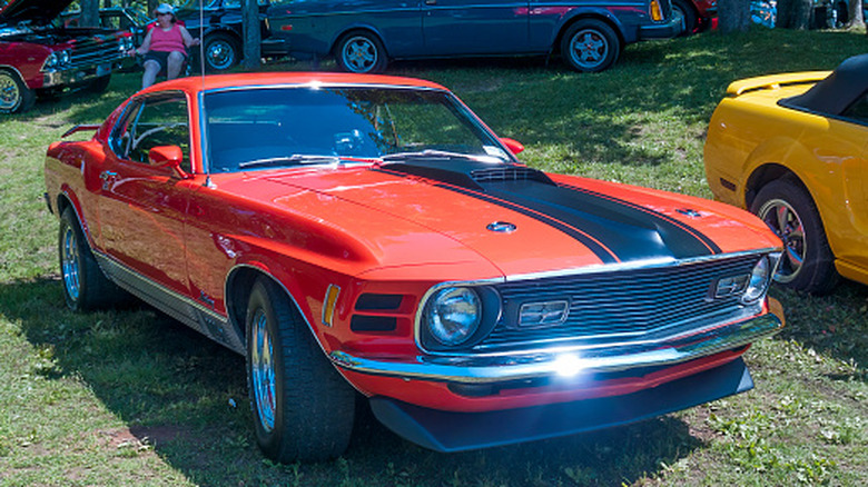 A red 1970 Ford Mustang Mach 1 hangin' out at a car show.