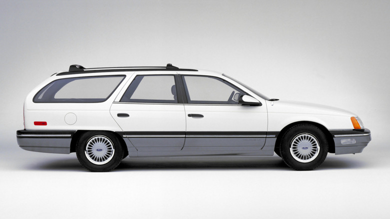 A side-profile shot of a white 1986 Ford Taurus station wagon in a studio