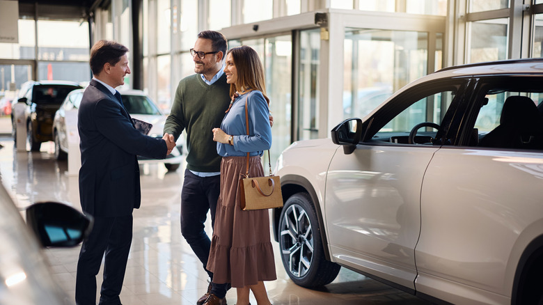 dealership salesperson talks with a couple of potential customers