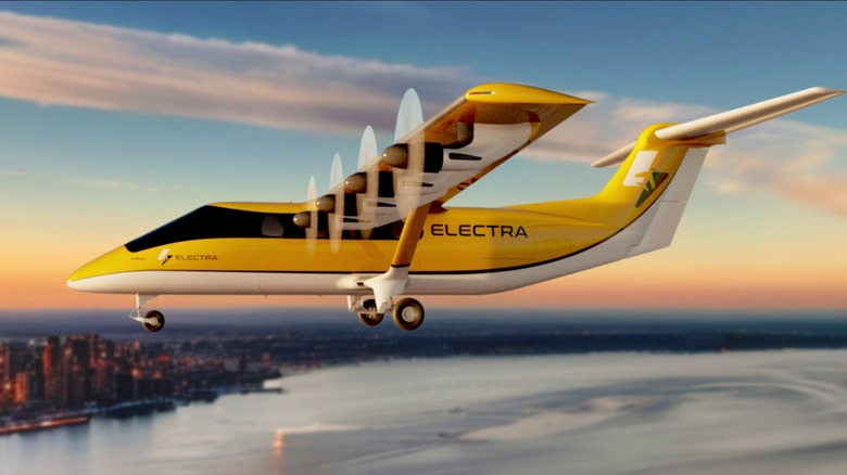 An Electra hybrid-electric aircraft flying over water with a city in the background