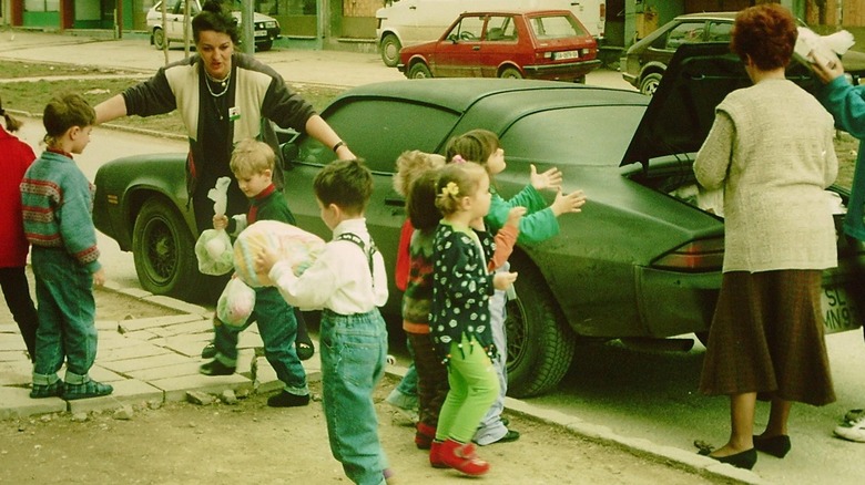 Women and children unloading humanitarian supplies from the Ghost Camaro