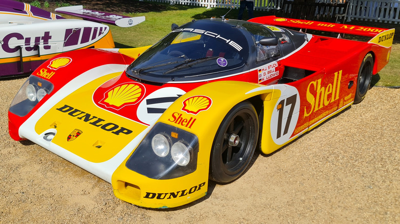 1988 Porsche 962 parked on gravel with Dunlop and Shell orange and yellow colors