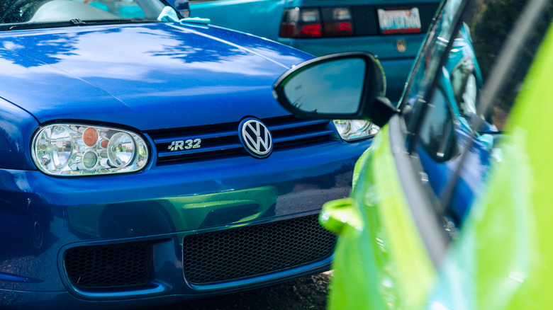 A blue Volkswagen GTI R32 is partially obscured by a neon green car in the foreground