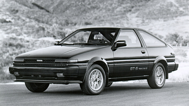 A black and white press photo of a 1986 Toyota Corolla GT-S AE86 Liftback, front three-quarter view.