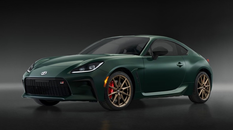 A studio shot of a 2025 Toyota GR86 Hakone Edition finished in deep Ridge Green, featuring bronze multi-spoke alloy wheels and red brake calipers.