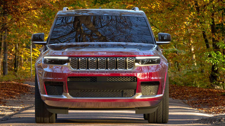 A red Jeep Wagoneer L driving through a wooded landscape