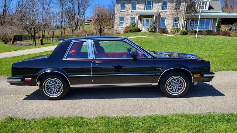 A $32,000 black 1980 Pontiac Phoenix LJ 4-Speed, pictured in front of a two-story home.