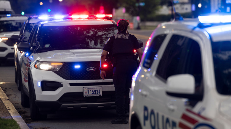 Police cars parked roadside with police lights turned on.