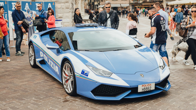 An Italian Lamborghini Huracan police car parked near a crowd.