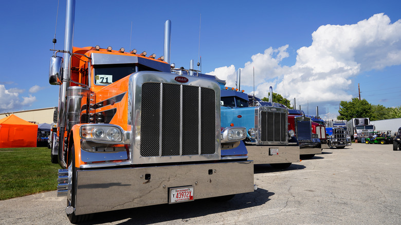Row of parked semi trucks showing off polished radiators