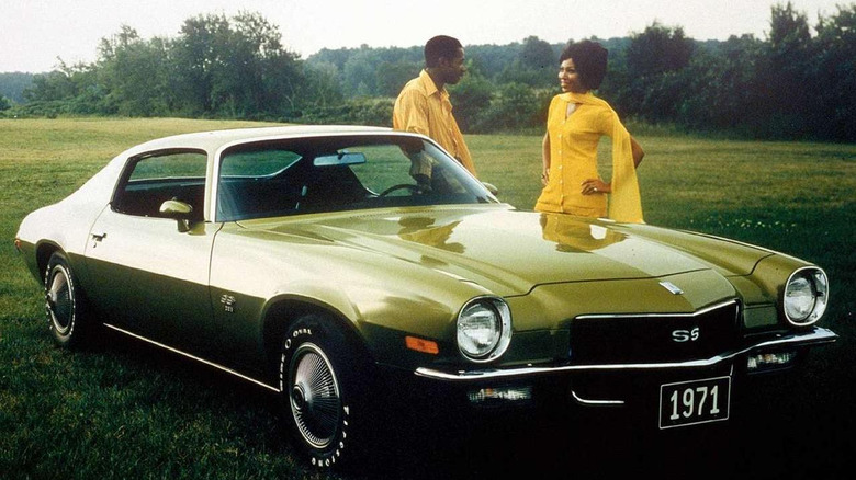 Pontiac SS in green parked in a field while a man and a woman dressed all in yellow smile