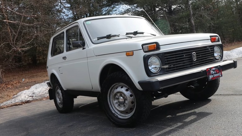 A 1994 Lada Niva in white with a hand crank opening on the bumper