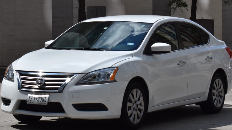 A white Nissan Sentra on a city street.