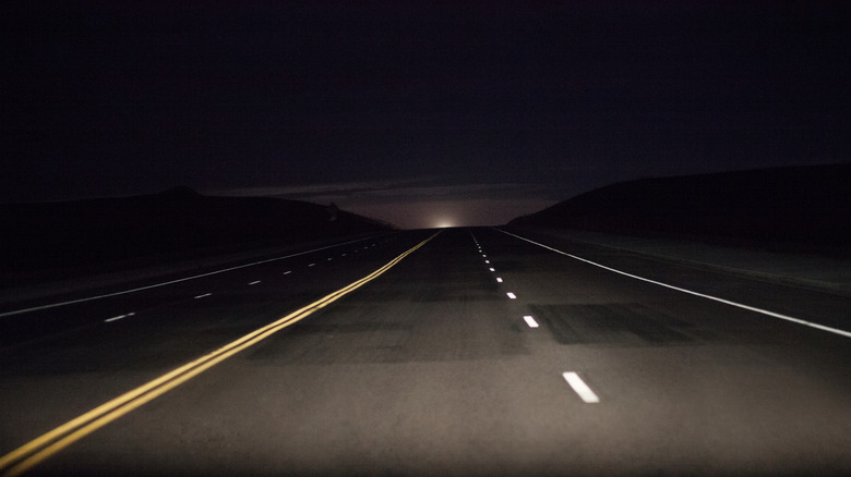 Dark country road in the Wyoming countryside with the moon just peeking above the horizon.