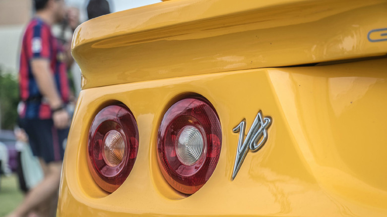 The badge and taillights of a yellow Lotus Esprit V8 sports car