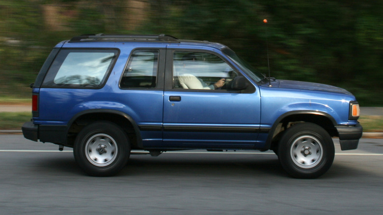 A blue Mazda Navajo in profile driving on the road