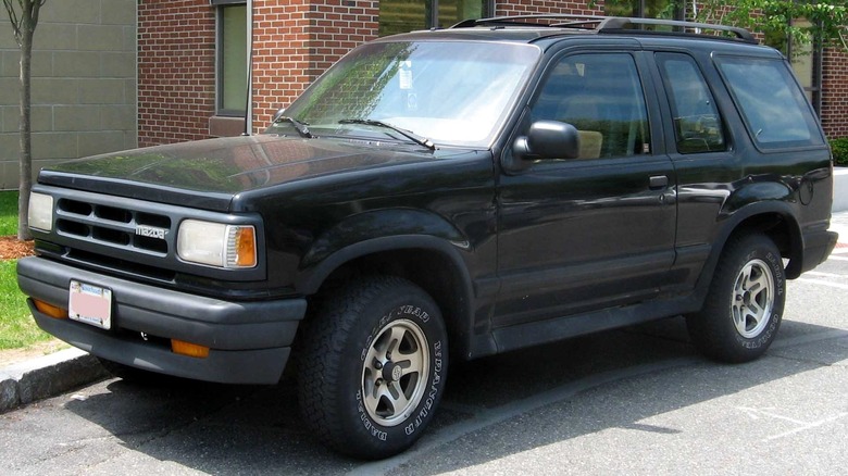 A front 3/4 view of a black Mazda Navajo parked in front of a brick building