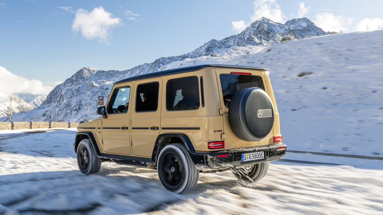 A modern Mercedes G-Class off-roading through snow