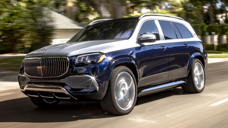 A Mercedes-Maybach GLS cruising down a tree-lined street on a sunny day.