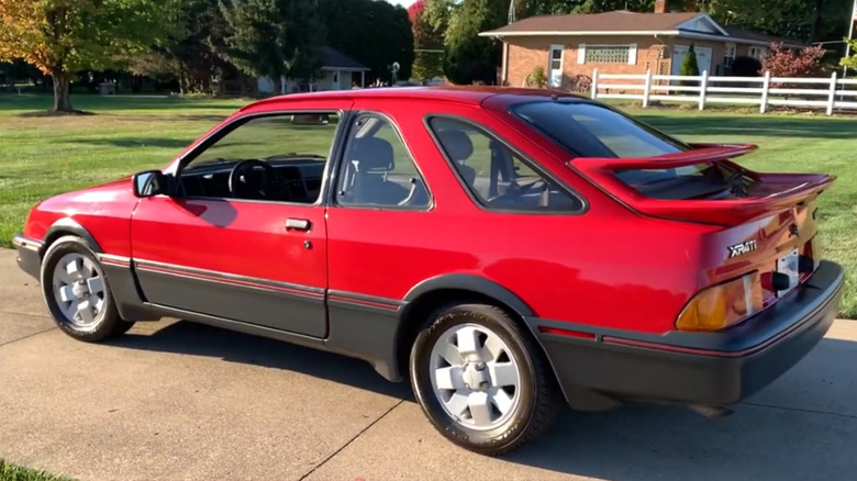 Rear 7/8 photo of a red Merkur XR4Ti in bright sun.