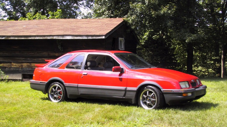 Front 7/8 photo of a red Merkur XR4Ti parked on grass.