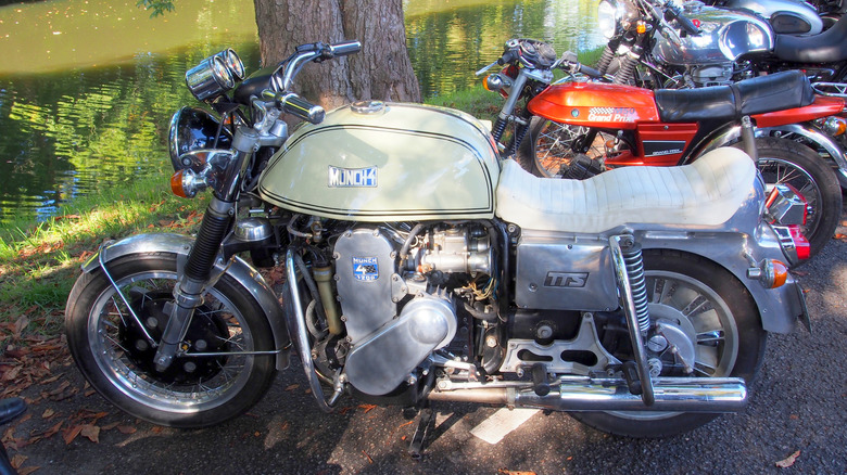 A white Münch Mammut TTS 1200 next to a line of motorcycles by a pond