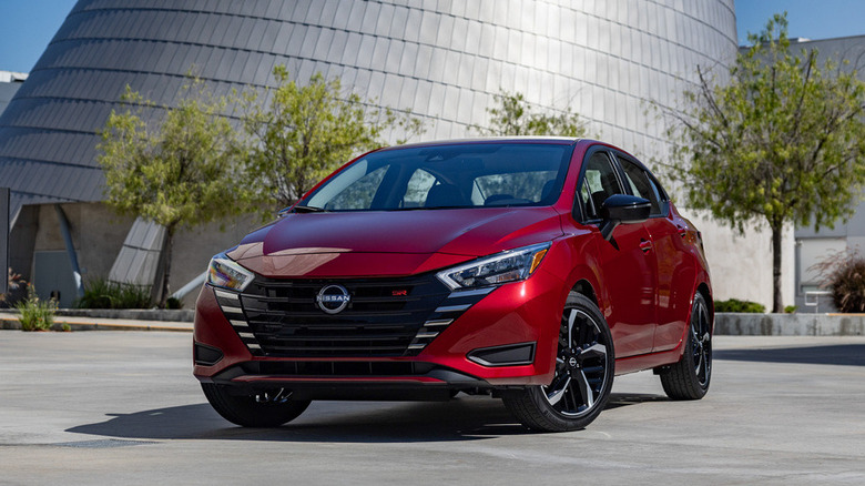 Nissan Versa parked in front of trees and a building