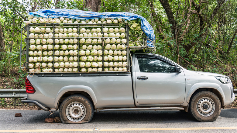 An overloaded pickup with a burst rear tire on the roadside