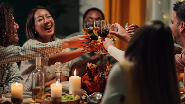 A Thanksgiving dinner where guests are toasting with their alcoholic drinks