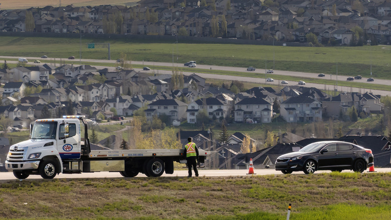 A tow truck driver at the scene of a disabled vehicle.