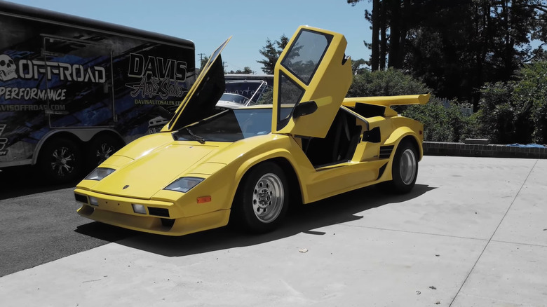 A Lamborghini Countach kit car with its doors open outside