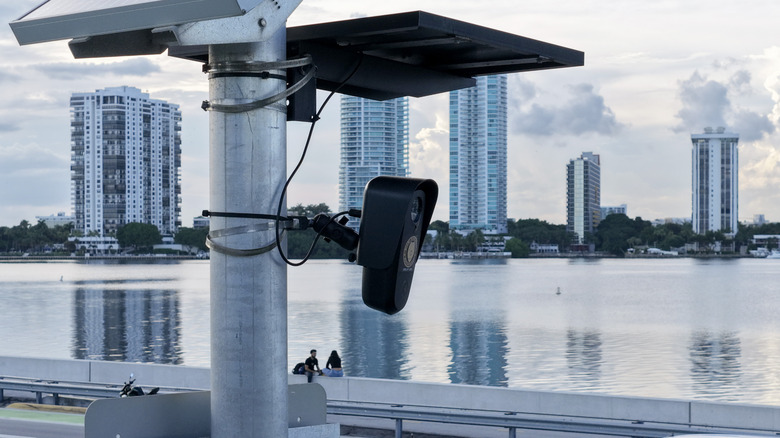 A flock camera watches over the citizens of Miami, Florida from a utility pole by the water.