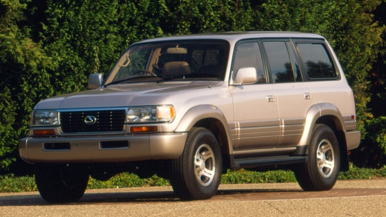The side of a 1997 Lexus LX 450 with bushes in the background.