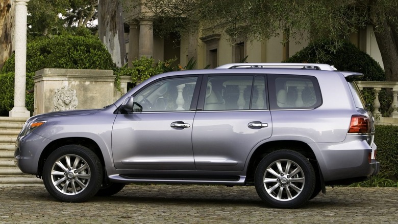 A side view of a 2008 Lexus LX 570 parked near an old house.