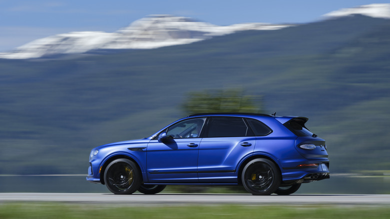 Side shot of a satin blue Bentley Bentayga at speed.