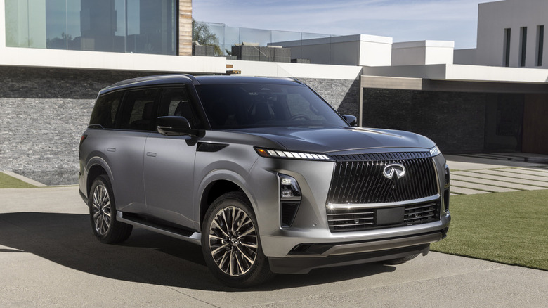 Front 3/4 of 2025 Infiniti QX80 full-size SUV parked in daytime near modern buildings