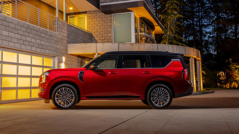 2025 Nissan Armada Platinum Reserve with two-tone exterior parked in driveway of modern house at night