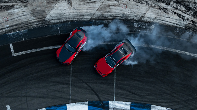 Two cars drifting around a racetrack