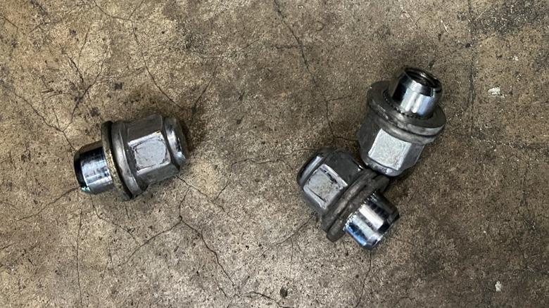 three chrome-capped lug nuts on a concrete floor
