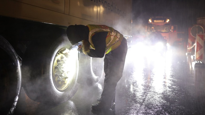 Policewoman checks brakes and tires of truck