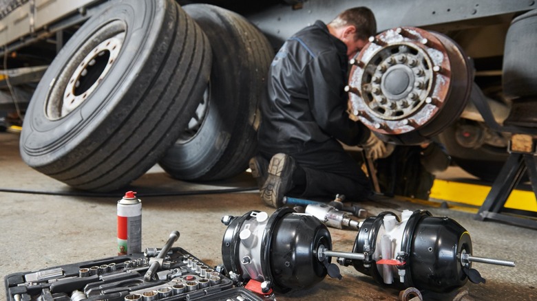 Mechanic servicing brakes on a truck in a workshop